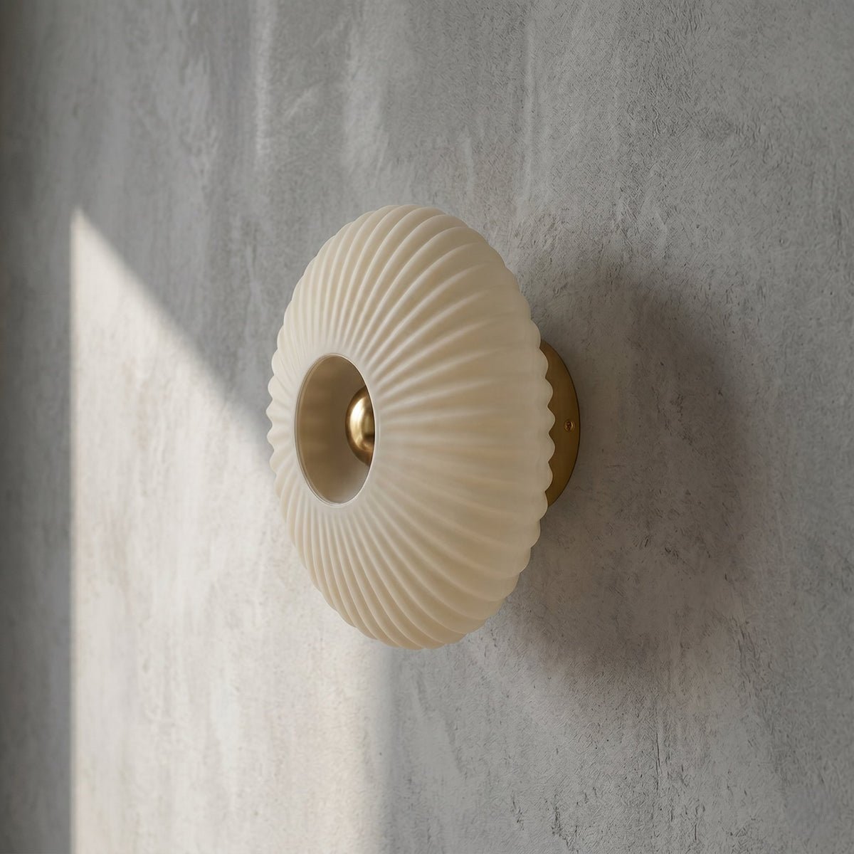 Luminaire mural rond en verre opalin plissé, avec son support discret en laiton, offrant une touche de sophistication intemporelle.