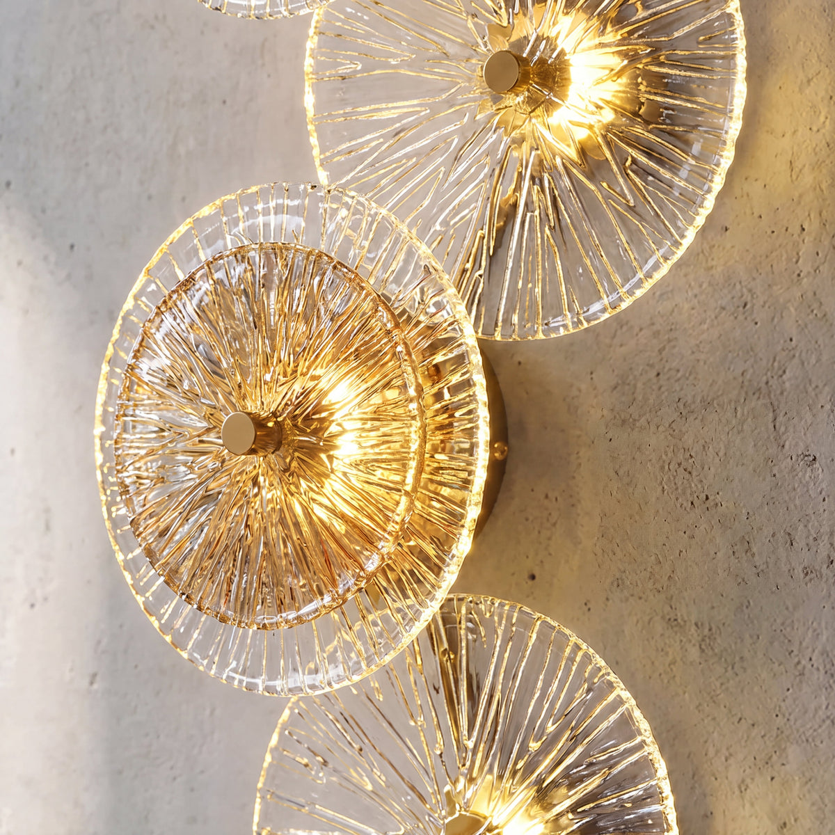 Vue rapprochée d'une applique murale en verre texturé effet feuille de lotus, alternant disques clairs et ambrés, illuminant un mur moderne.