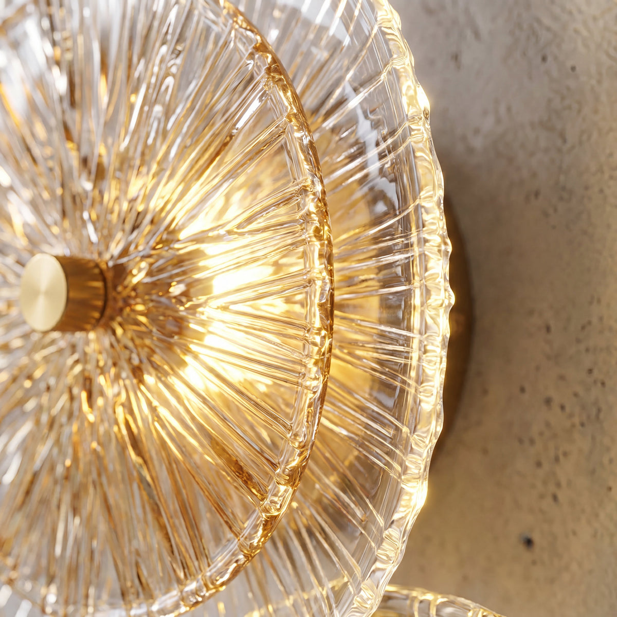 Applique murale allumée diffusant une lumière LED chaude, mettant en valeur les motifs uniques du verre et l'éclat subtil du métal doré sur un mur.