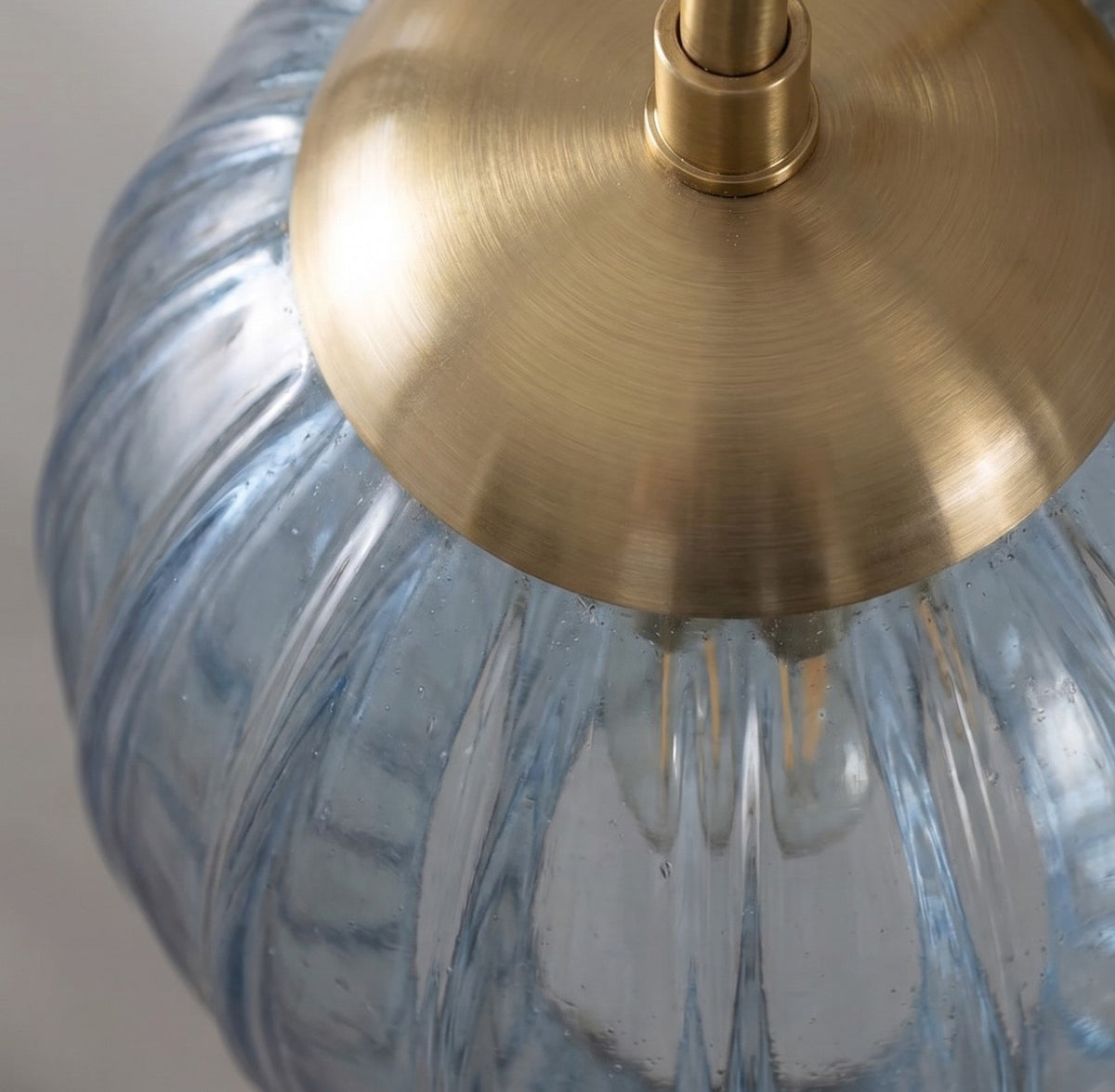 Détail du culot E14 et de l'ampoule visible à travers le verre strié bleu-gris de cette applique murale, design intemporel.