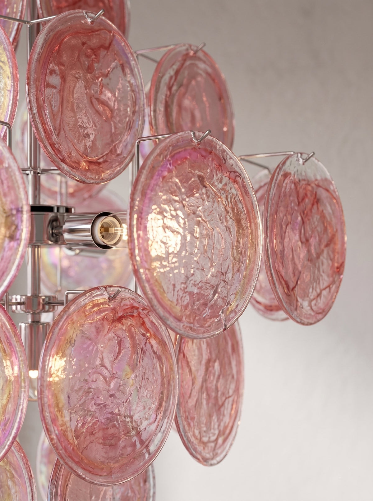 Détail rapproché des éléments en verre irisé rose, révélant les nuances chatoyantes et la texture délicate du lustre.