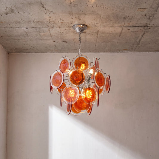 Lustre suspension style Murano moderne avec disques de verre soufflé rouge, éclairant un intérieur contemporain.