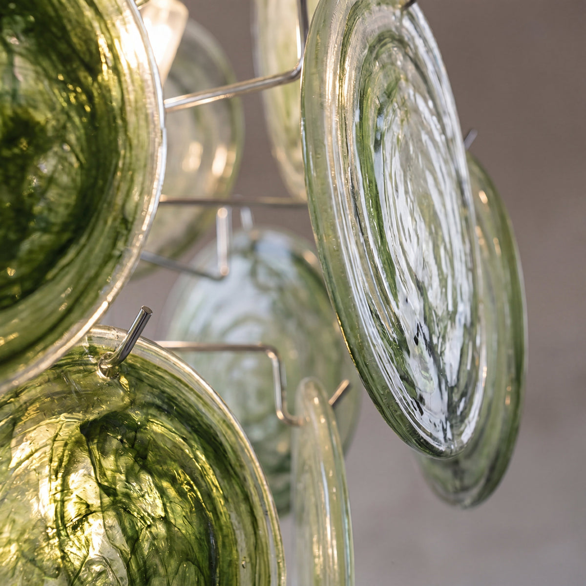 Silhouette du lustre vert foncé de 51cm de hauteur, projetant des reflets doux et chaleureux sur les murs d'une pièce contemporaine.