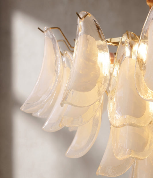 Vue rapprochée des pétales de verre soufflé opalin de ce lustre, capturant la lumière diffuse et la texture unique du matériau.