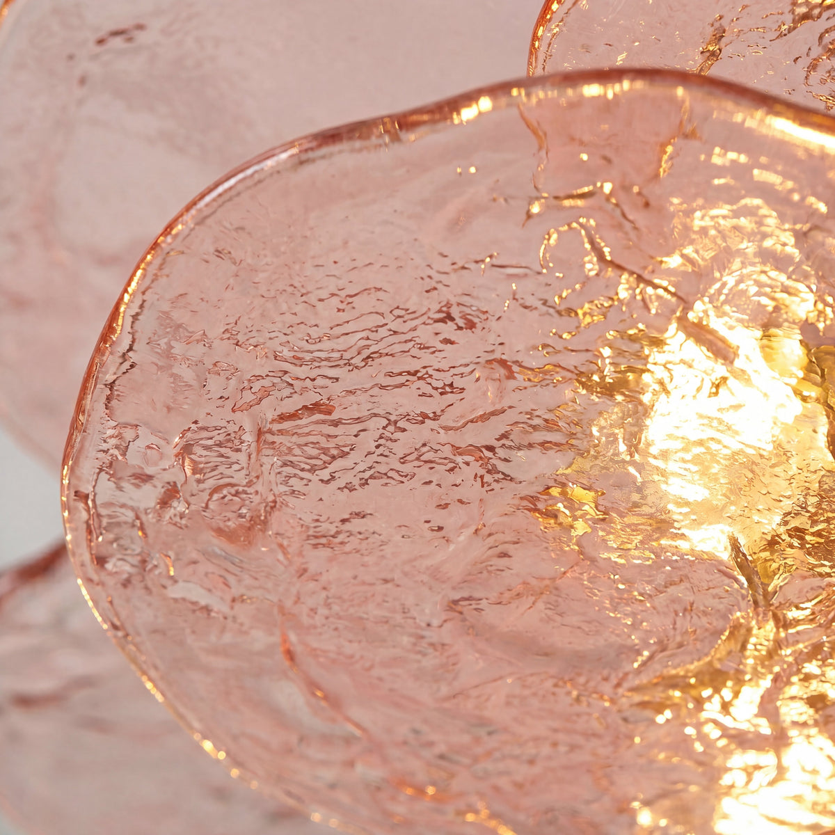 Gros plan sur la structure métallique dorée du lustre, supportant les éléments de verre, illustrant la qualité de fabrication.