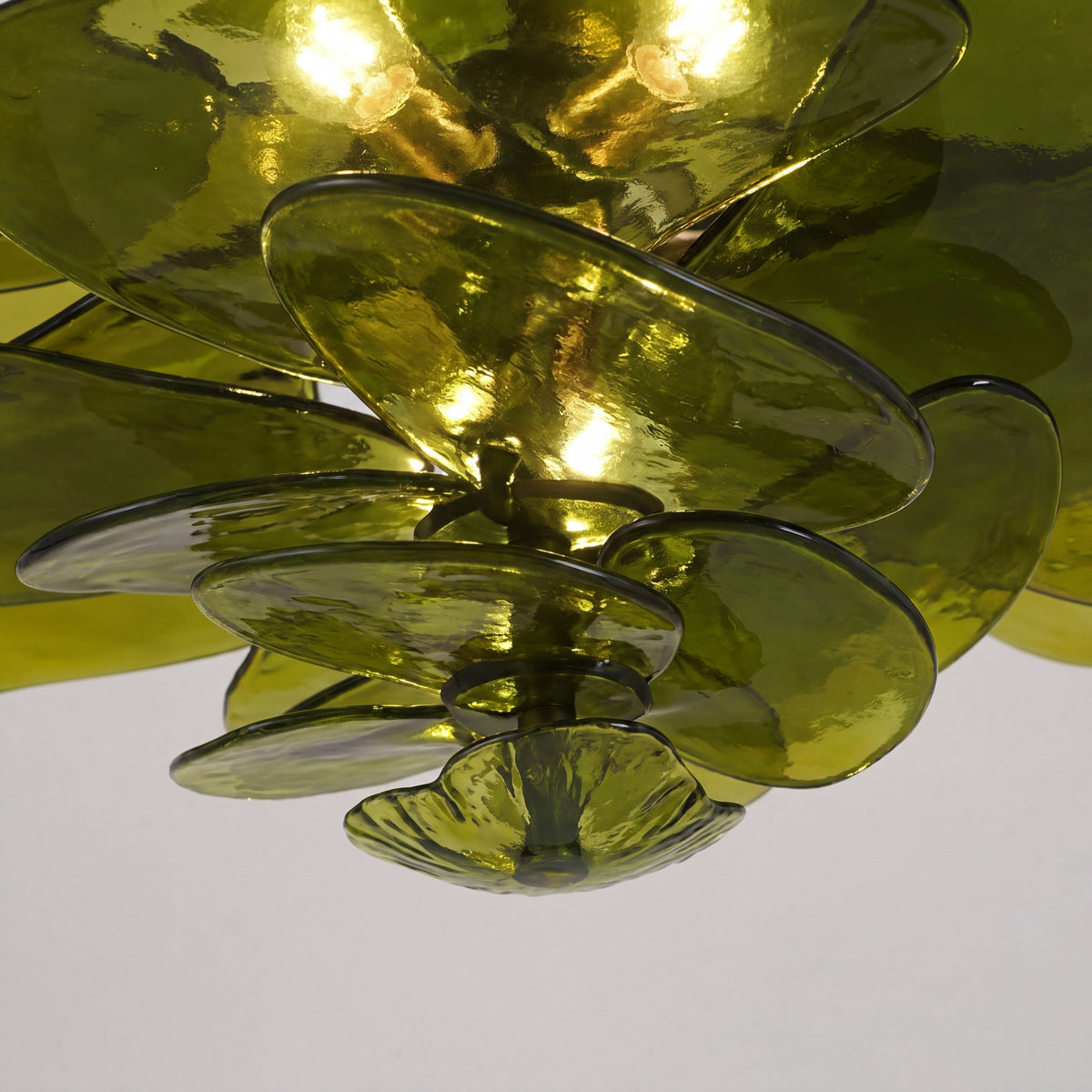 Vue rapprochée du lustre vert ambré, mettant en valeur les détails du verre soufflé et la finition plaquée du support métallique.