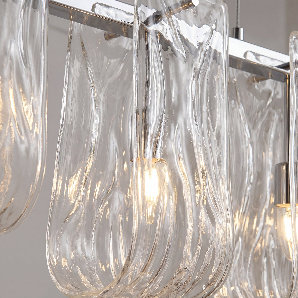 Gros plan sur la fixation au plafond en acier poli et le câble de suspension réglable de cette lampe élégante pour un réglage facile.
