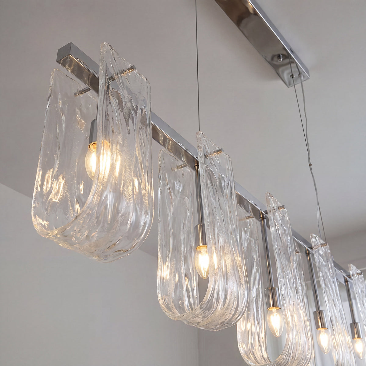 Vue détaillée de l'abat-jour en verre givré de la suspension, révélant la texture unique et l'effet de ruban lumineux.