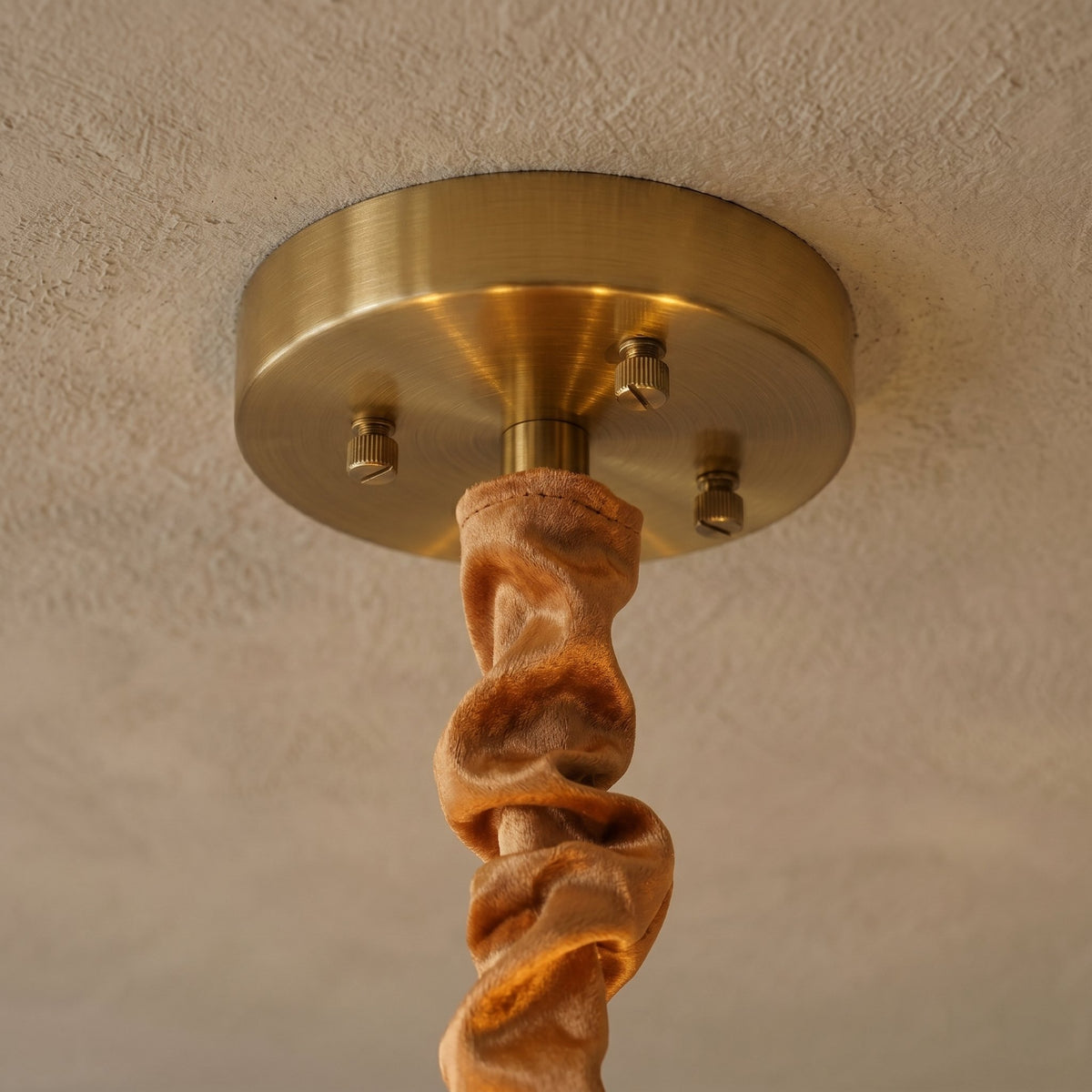 Angle rapproché du lustre, révélant la finition dorée de la structure métallique et la fixation de la chaîne réglable.