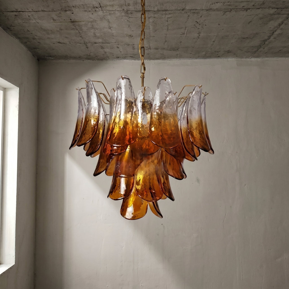 Profil du lustre Murano avec sa structure métallique dorée et ses multiples éléments de verre, diffusant une douce clarté.