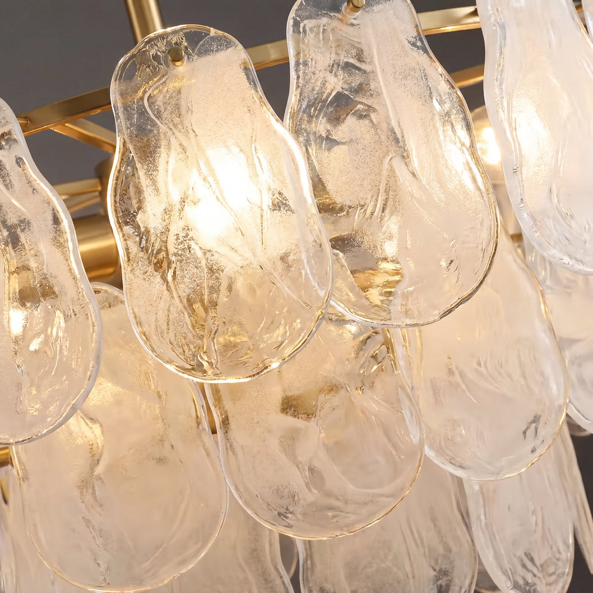 Lustre semi-encastré en laiton et verre clair, vu de côté, montrant ses multiples couches lumineuses et son design sophistiqué.