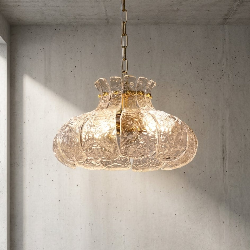 Lustre suspension floral style Murano, verre texturé clair et finition laiton poli, éclairant un salon moderne.