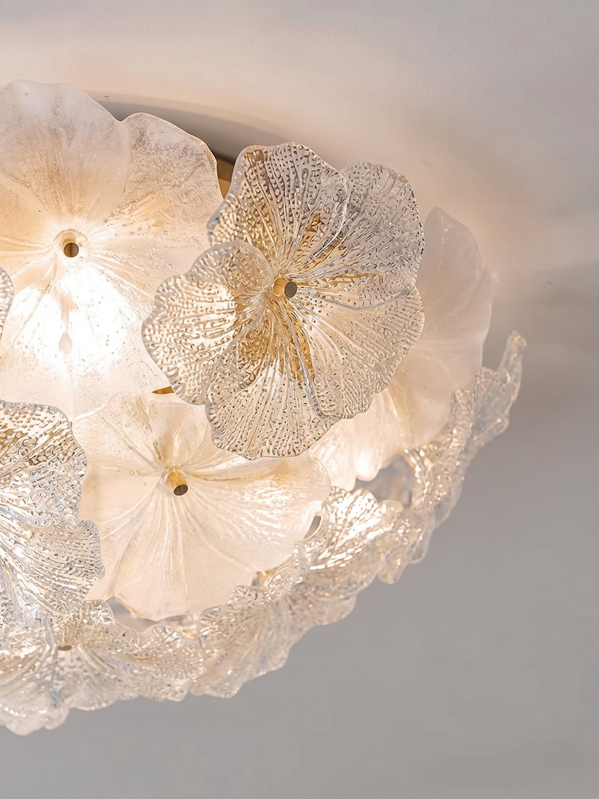 Image du luminaire allumé, montrant la diffusion homogène de la lumière LED à travers les pétales de verre givré.