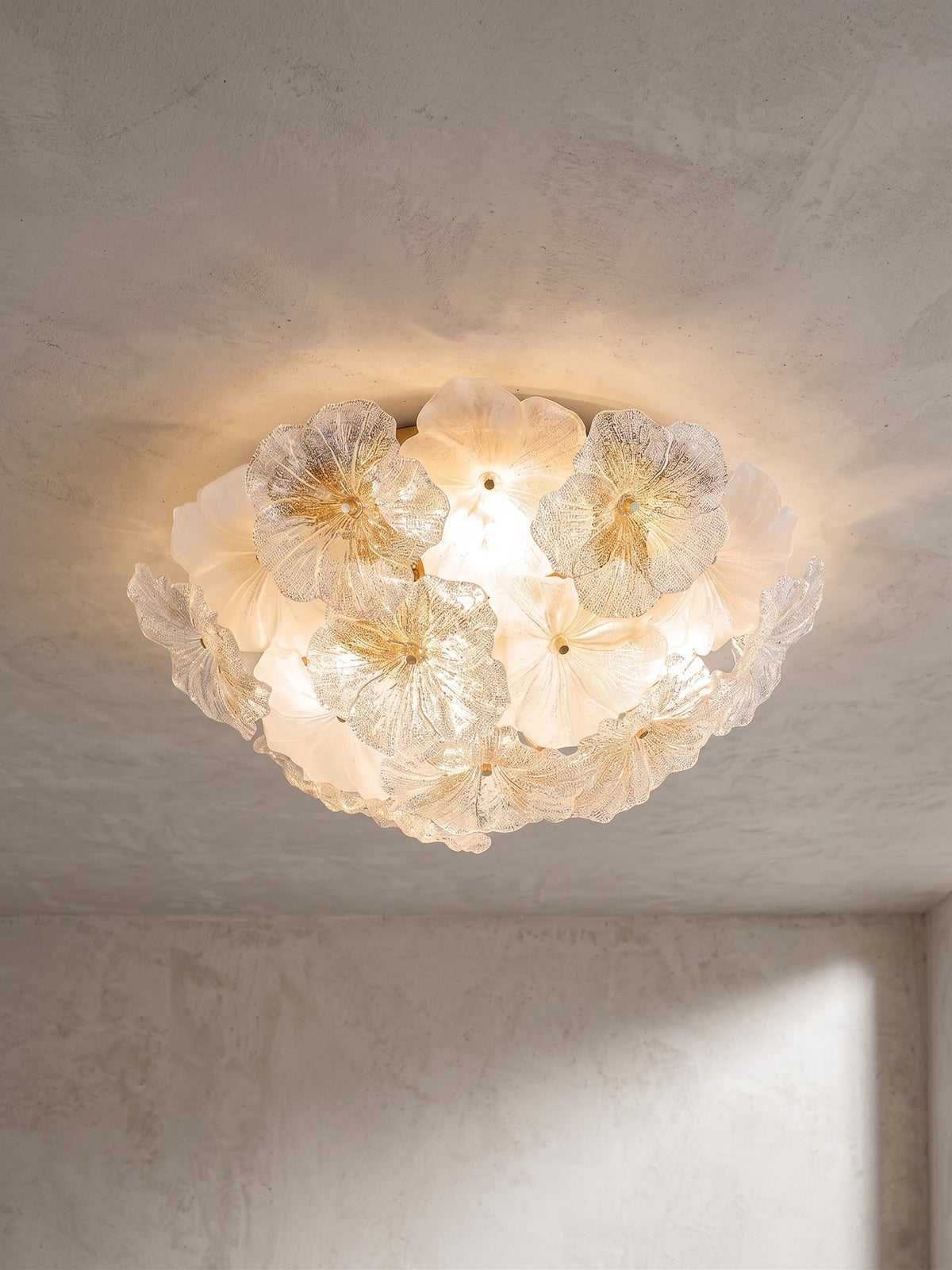 Lustre plafonnier moderne en verre soufflé, design floral, illuminant un salon avec une lumière douce et chaleureuse.
