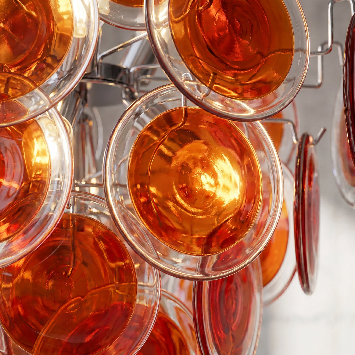 Vue de profil du lustre rouge orangé style Murano, montrant la superposition élégante des éléments en verre.