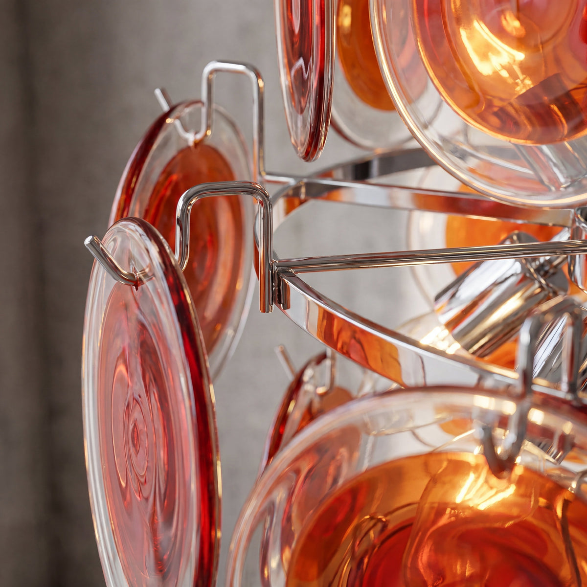 Détail des disques de verre soufflé teinté rouge orangé, capturant la lumière et créant une ambiance chaleureuse.