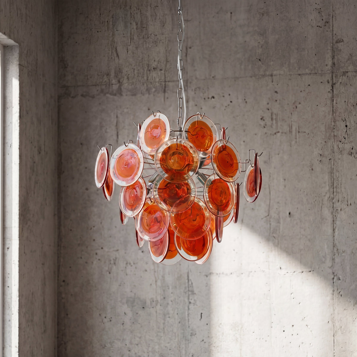 Gros plan sur la structure en fer poli du lustre, supportant les disques de verre soufflé rouge orangé avec finesse.