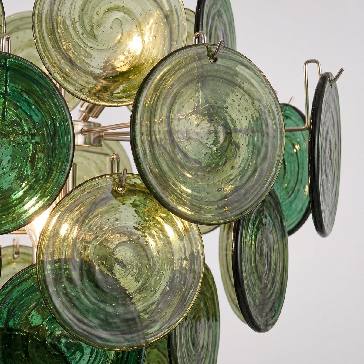 Angle de profil du luminaire, montrant l'agencement artistique des disques de verre et la structure en fer poli.