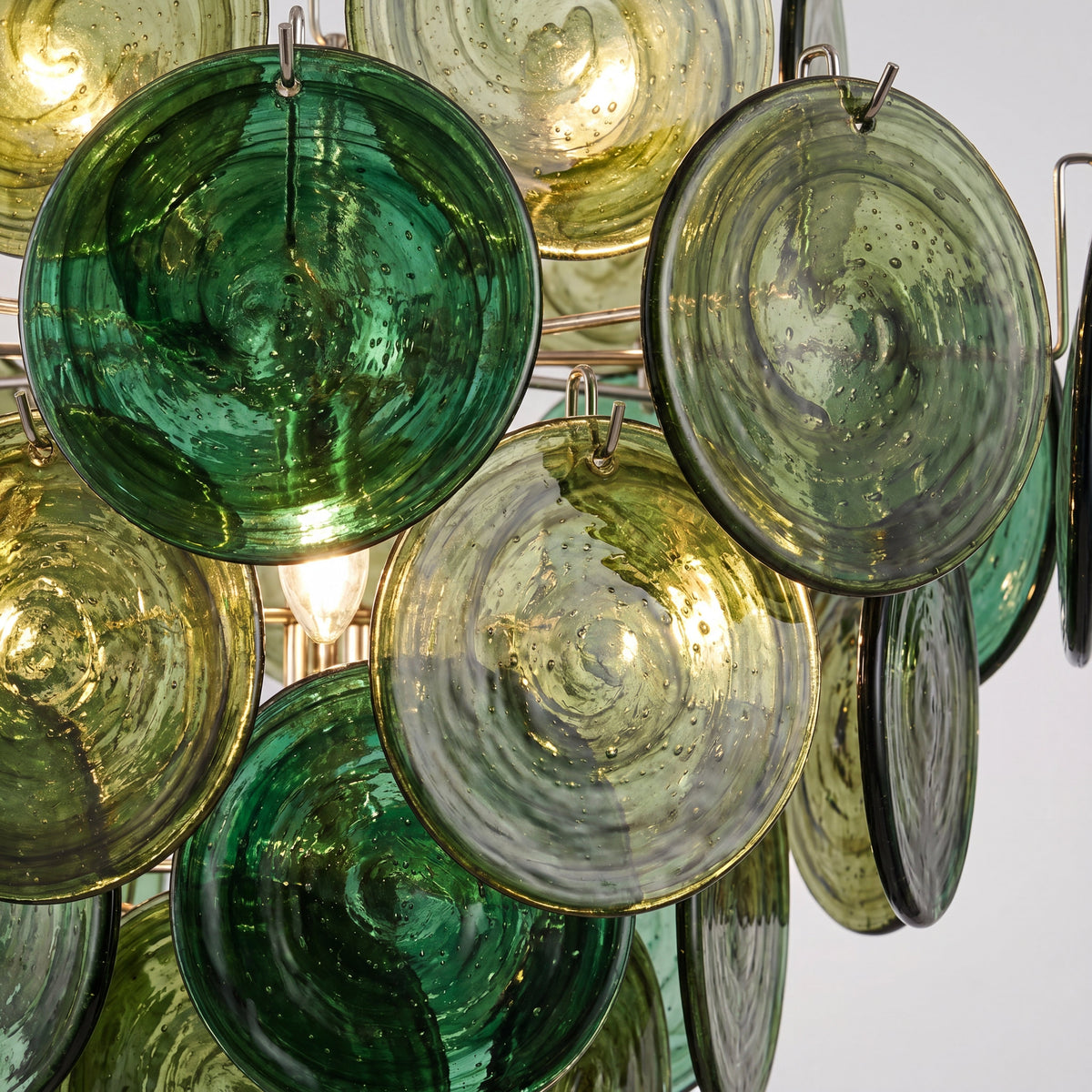 Vue détaillée des disques de verre teinté vert émeraude du lustre, reflétant délicatement la lumière ambiante de la pièce.