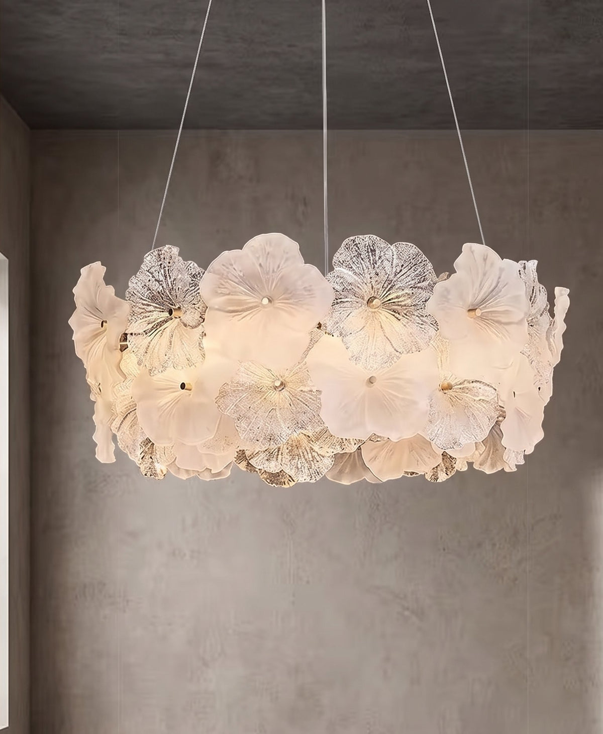 Lustre floral en verre opalin de style Murano, allumé, diffusant une lumière douce et chaleureuse dans un salon moderne.