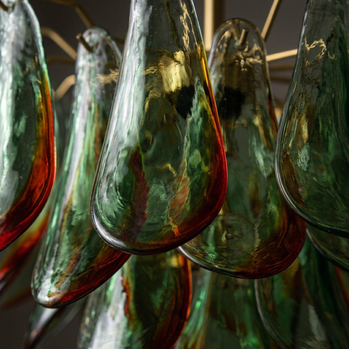 Vue rapprochée des délicats pétales de verre teinté du lustre, montrant les nuances de vert et les reflets ambrés chaleureux.