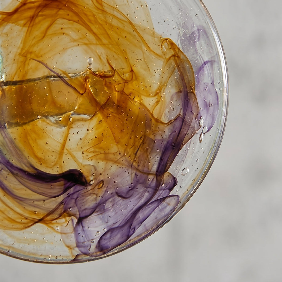 Lustre suspension allumé, projetant une lumière douce et colorée sur les murs, soulignant l'effet décoratif du verre irisé.