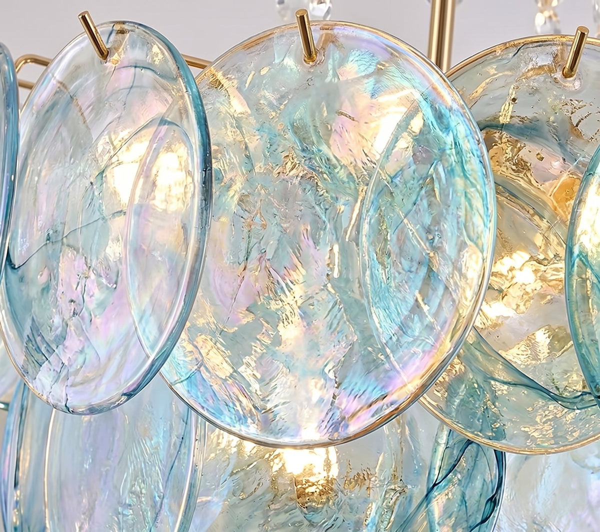Vue rapprochée des disques de verre irisé aux reflets bleu-vert du lustre, mettant en valeur leur texture unique et leur éclat subtil.