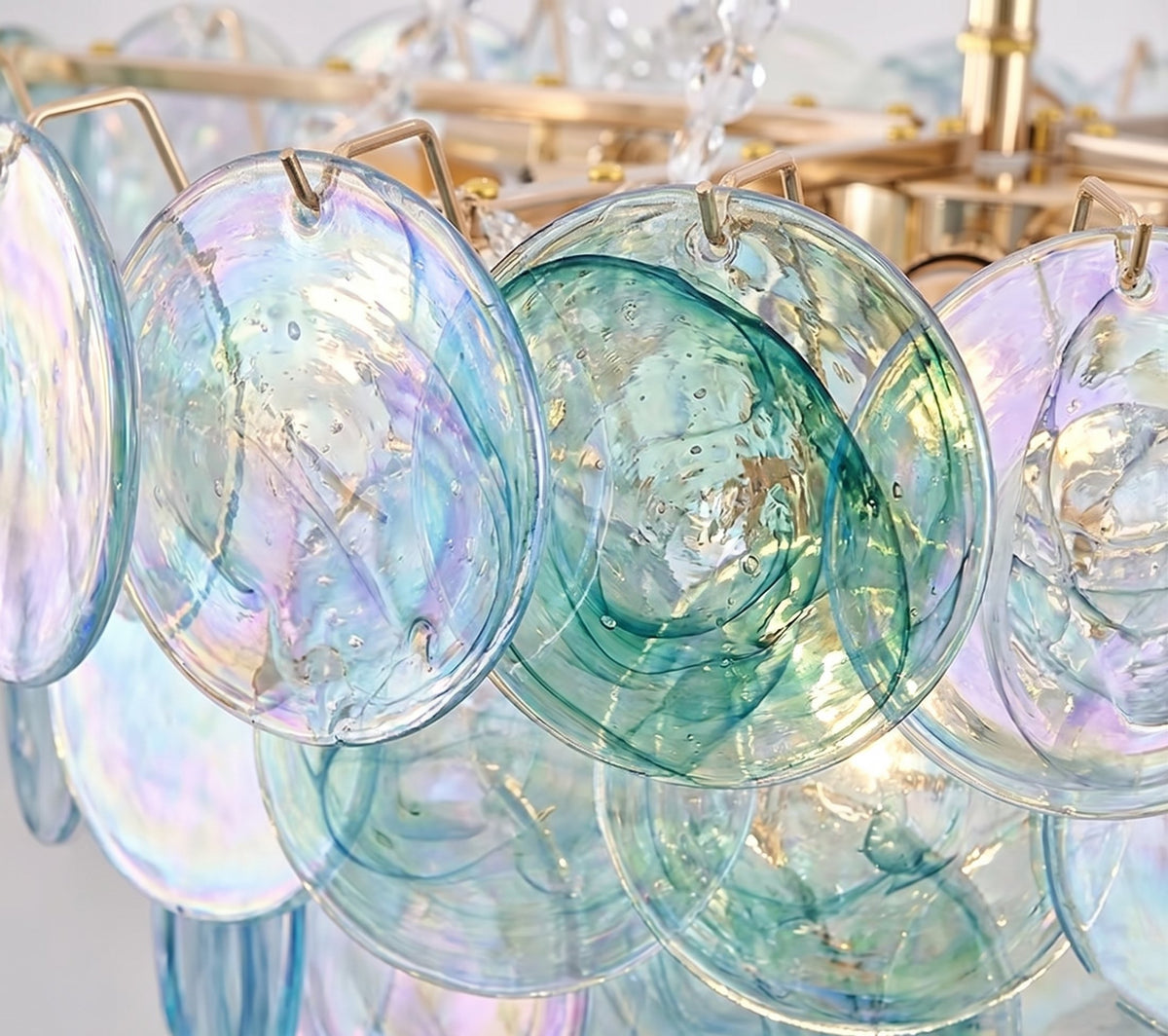 Gros plan sur le corps en fer plaqué doré et les perles de la chaîne réglable du lustre style Murano, symbole d'un savoir-faire raffiné.