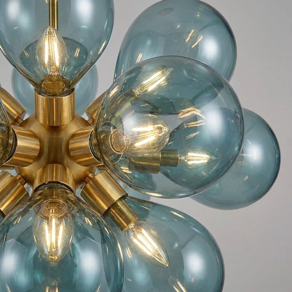 Détail des ampoules LED G9 incluses, visibles à travers le verre soufflé teinté bleu azur du lustre contemporain.