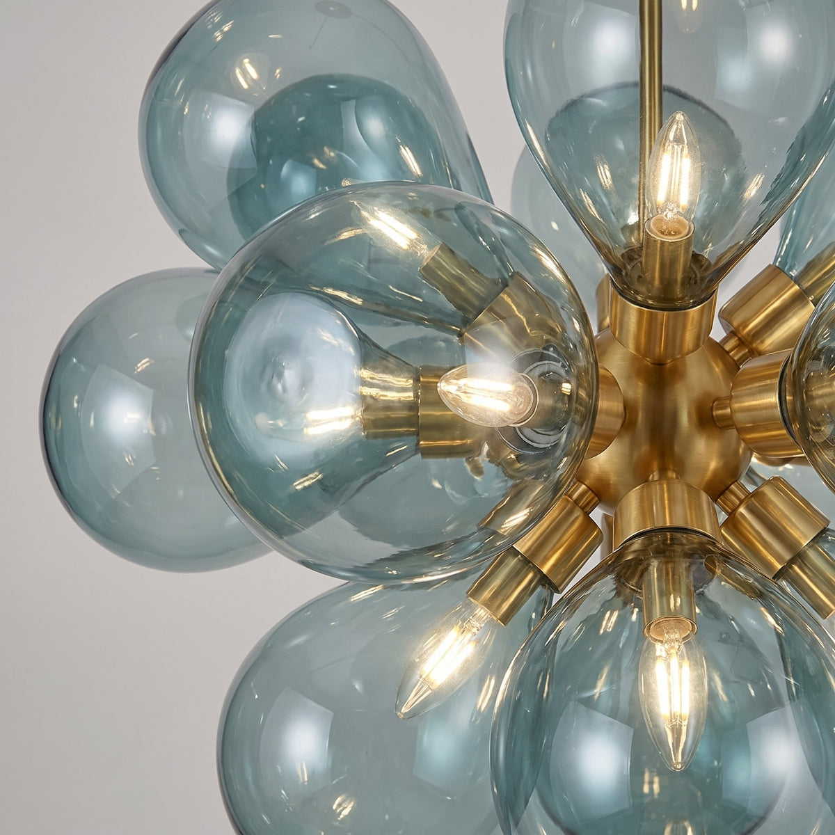 Vue rapprochée du lustre, montrant les 18 abat-jours en verre soufflé bleu azur et la structure en laiton doré.