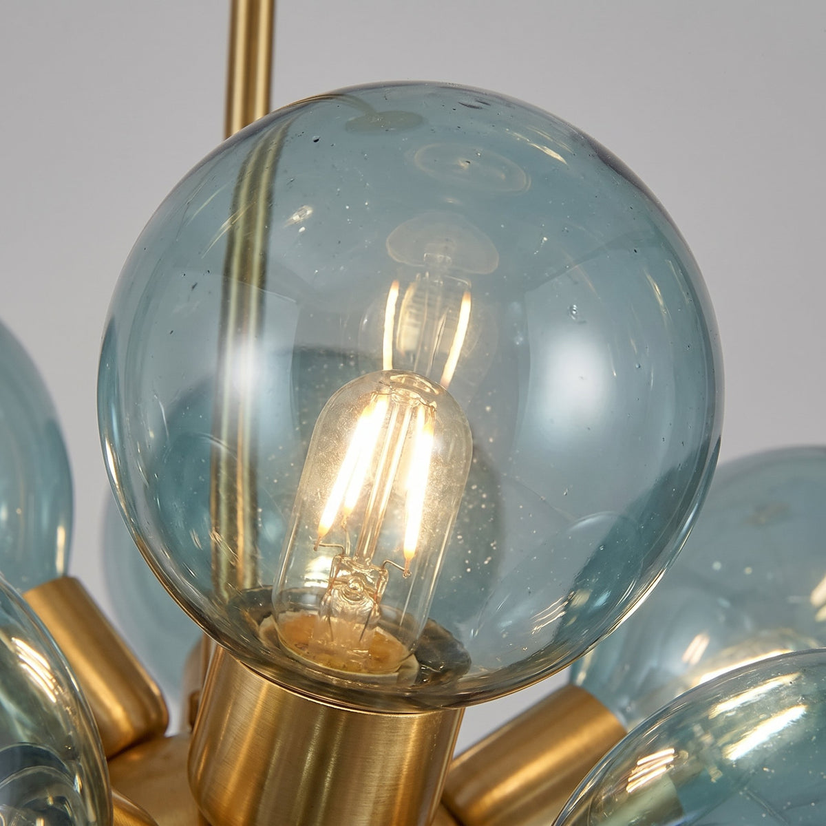 Photographie du lustre éteint, révélant la transparence et la teinte délicate du verre soufflé bleu azur.