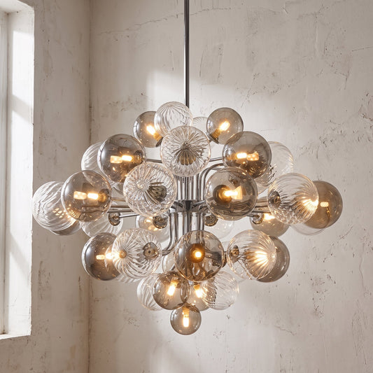 Vue d'ensemble du lustre style Murano moderne, avec ses 47 boules de verre gris fumé, éclairant un salon contemporain.
