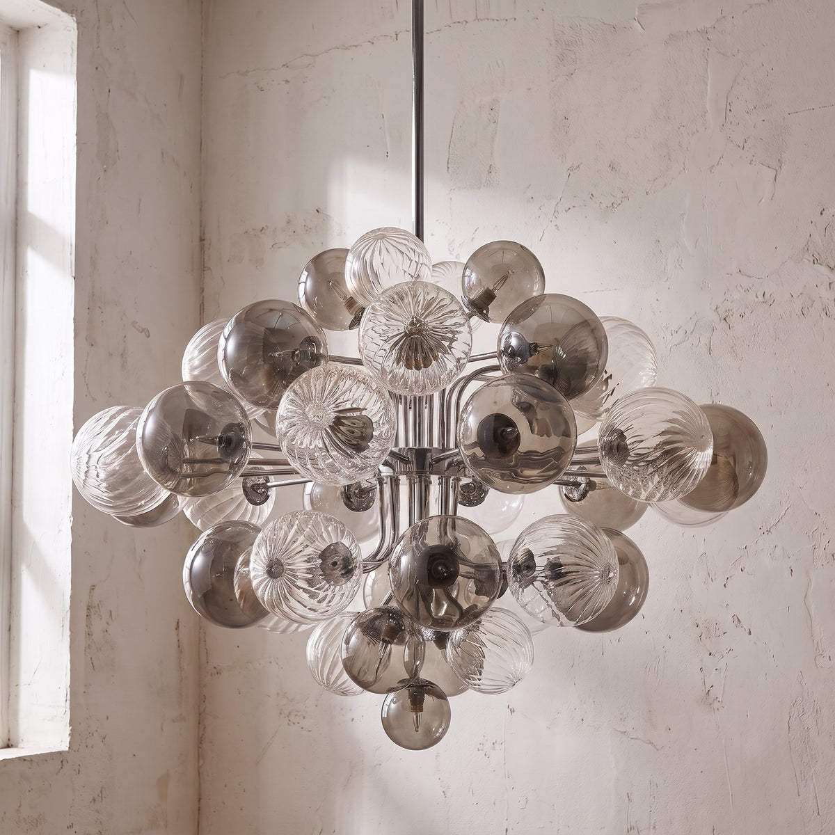 Lustre allumé, diffusant une lumière chaude et douce à travers ses 19 ampoules LED G9, créant une ambiance cosy et raffinée.