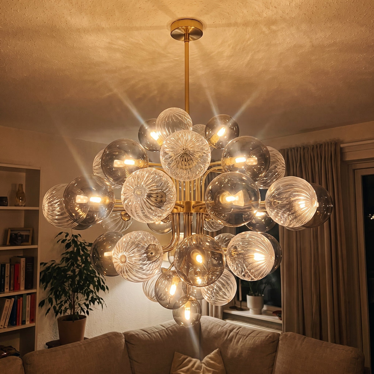 Détail des boules de verre soufflé gris fumé du lustre, certaines lisses, d'autres texturées, reflétant la lumière ambiante.