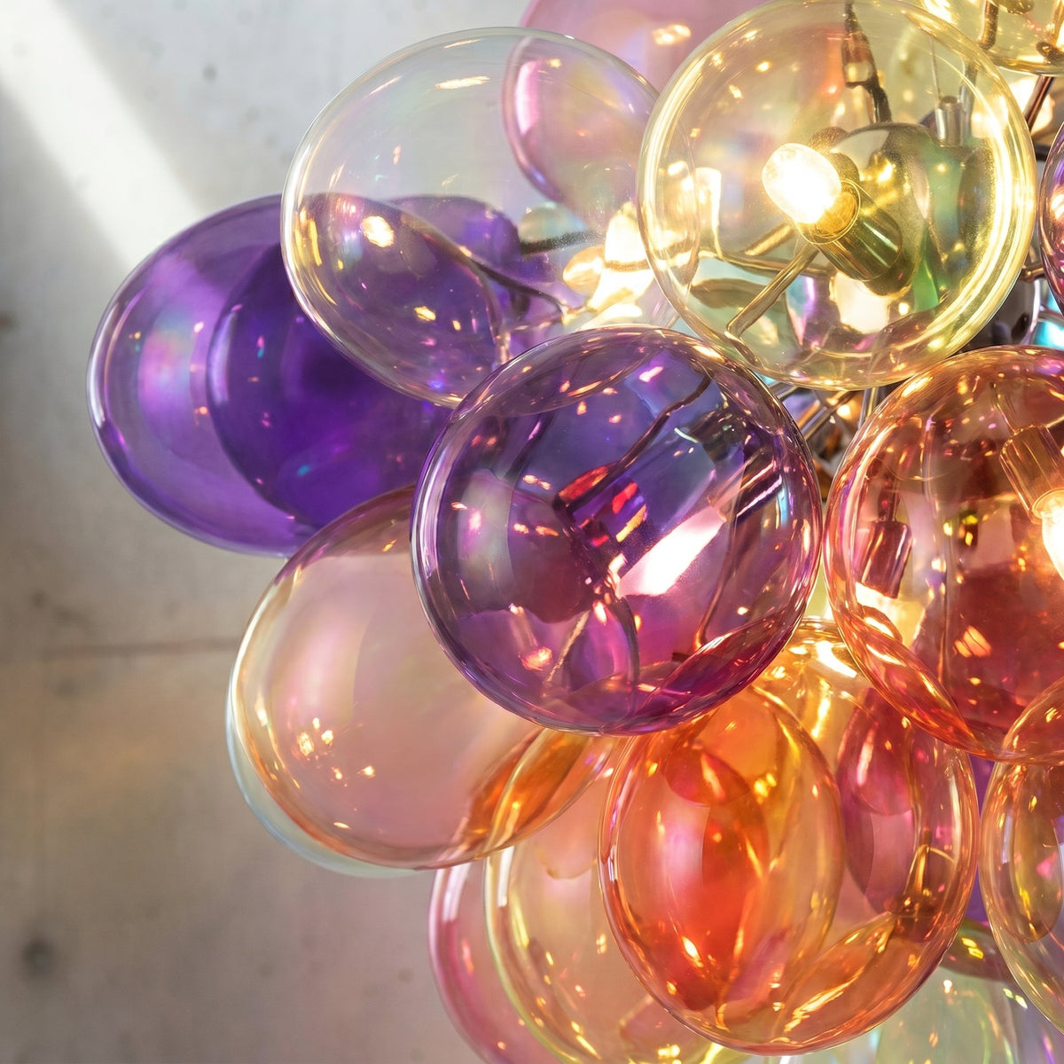 Vue rapprochée du lustre style Murano, montrant la richesse des couleurs des bulles de verre. La lumière LED souligne la beauté des reflets.