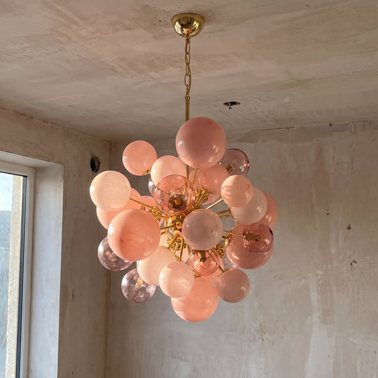 Lustre suspension moderne en verre rose poudré, design sphérique pour salon élégant. Ce luminaire unique crée une ambiance douce.