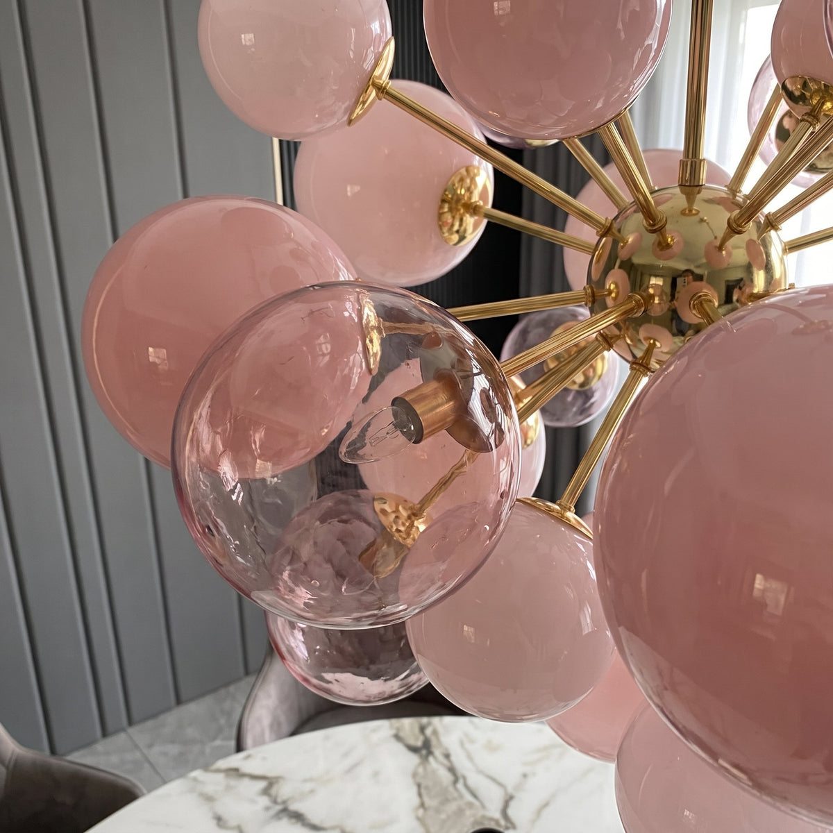 Le lustre moderne en verre rose poudré, avec ses dimensions de 80x80cm, s'intègre parfaitement dans une villa spacieuse.