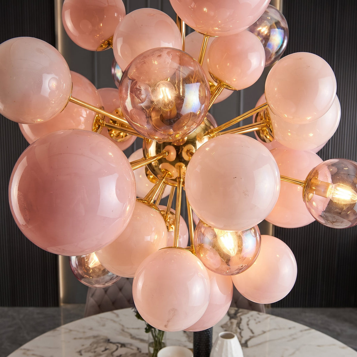 Suspension luminaire rose poudré illuminant un intérieur contemporain, offrant un éclairage chaleureux et décoratif. Pièce maîtresse.