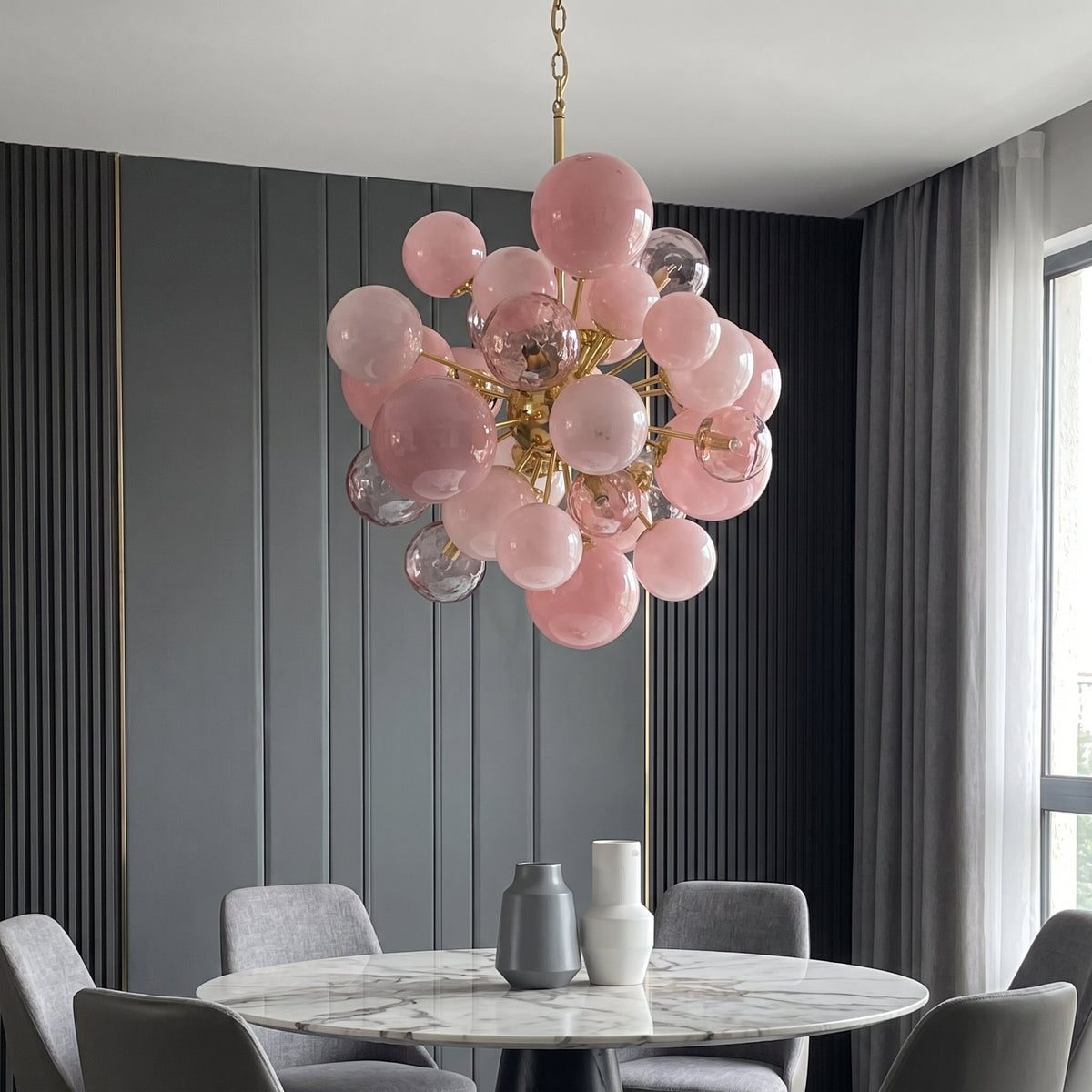 Détail de la chaîne de suspension ajustable du lustre, reliant le plafonnier à la grappe de sphères lumineuses. Finition soignée.