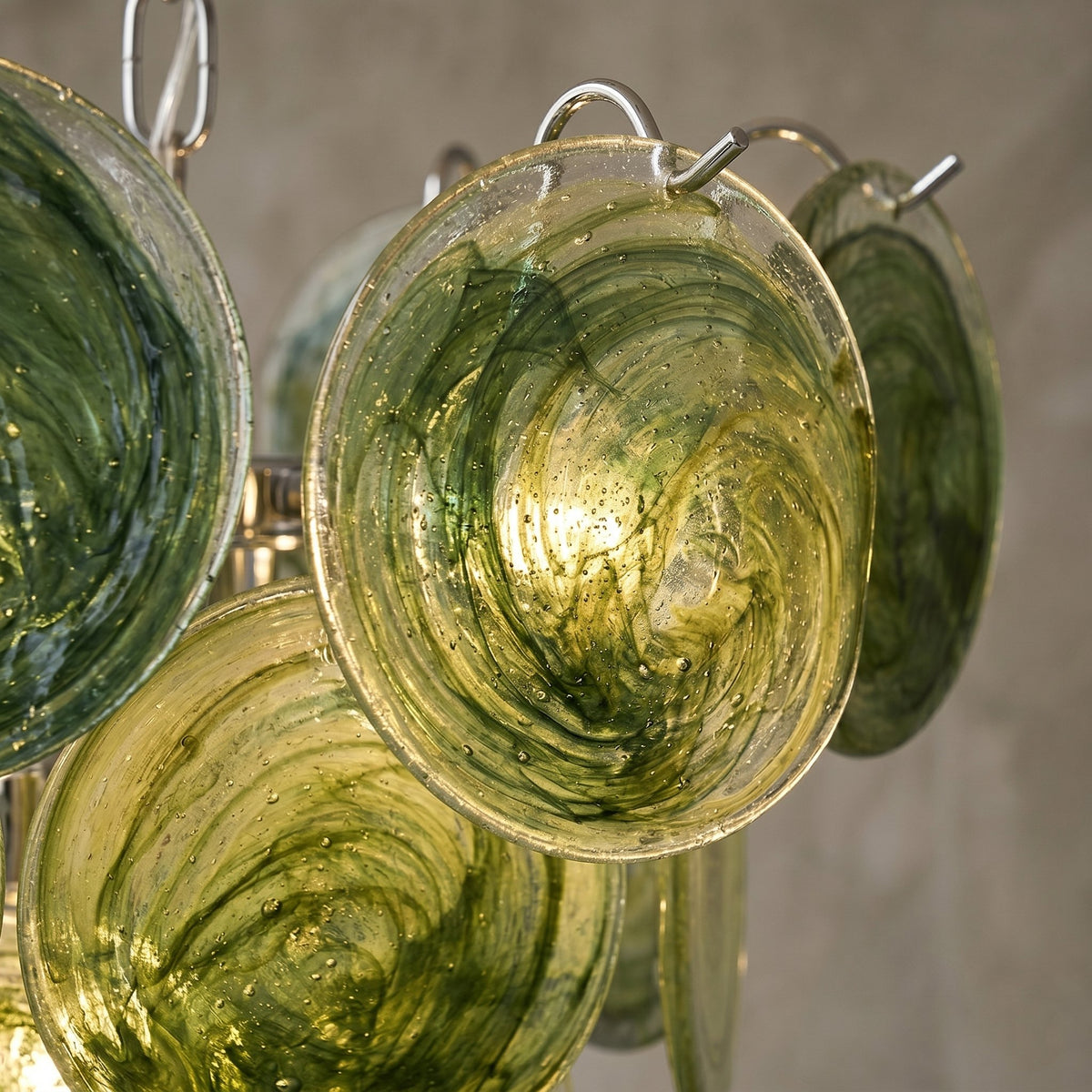 Détail de la structure métallique en fer poli soutenant les éléments en verre vert céladon, finition soignée.