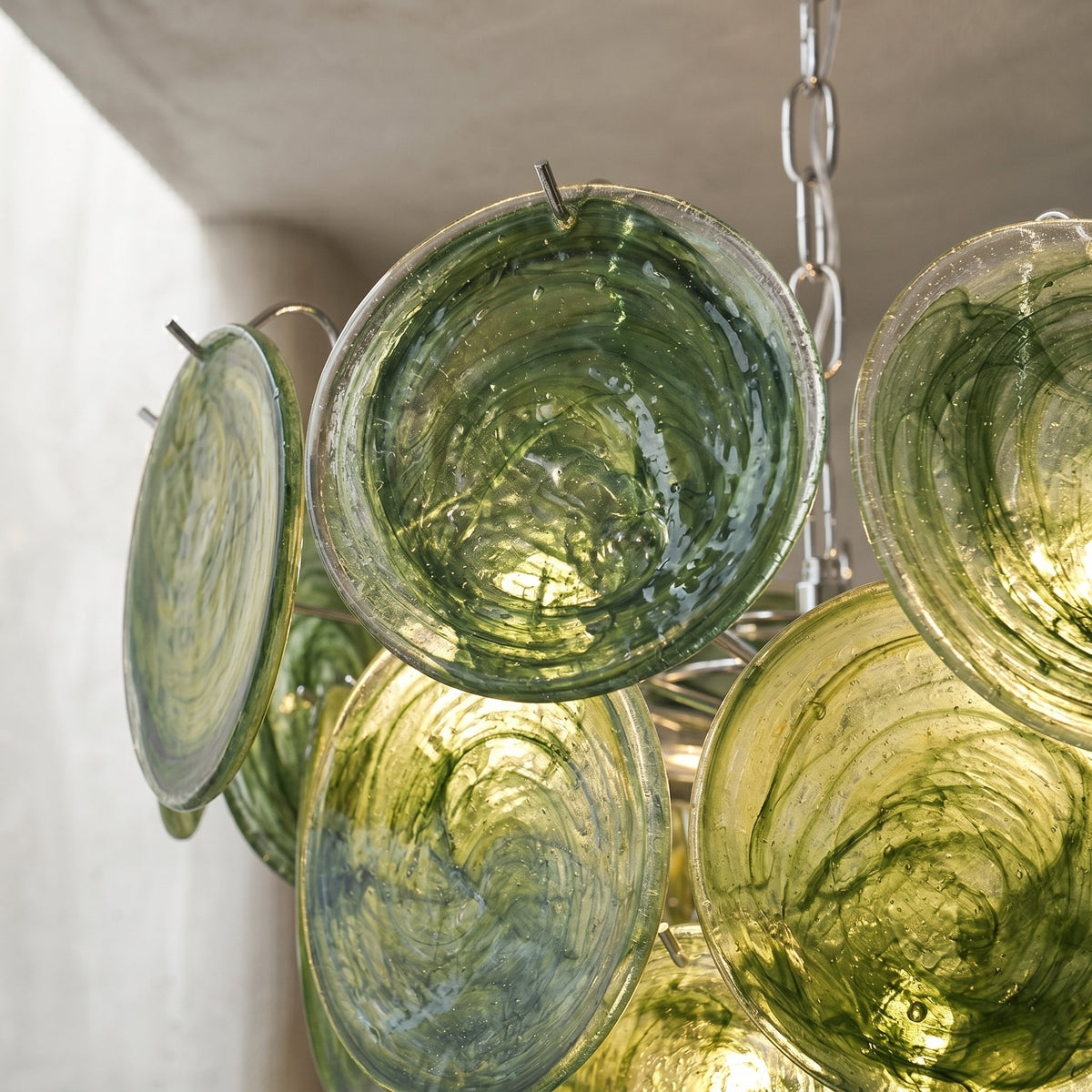 Vue rapprochée des disques de verre vert céladon du lustre, révélant la texture et les reflets inspirés de Murano.