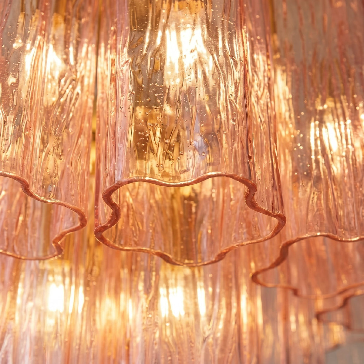 Vue rapprochée des tubes de verre rose texturé du lustre, révélant la finesse du style Art Déco et la qualité du matériau.